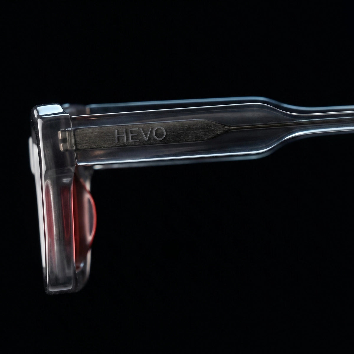 A close-up studio shot of a transparent cosmetic applicator tip with the brand name HEYO embossed vertically on the handle, set against a solid black background.