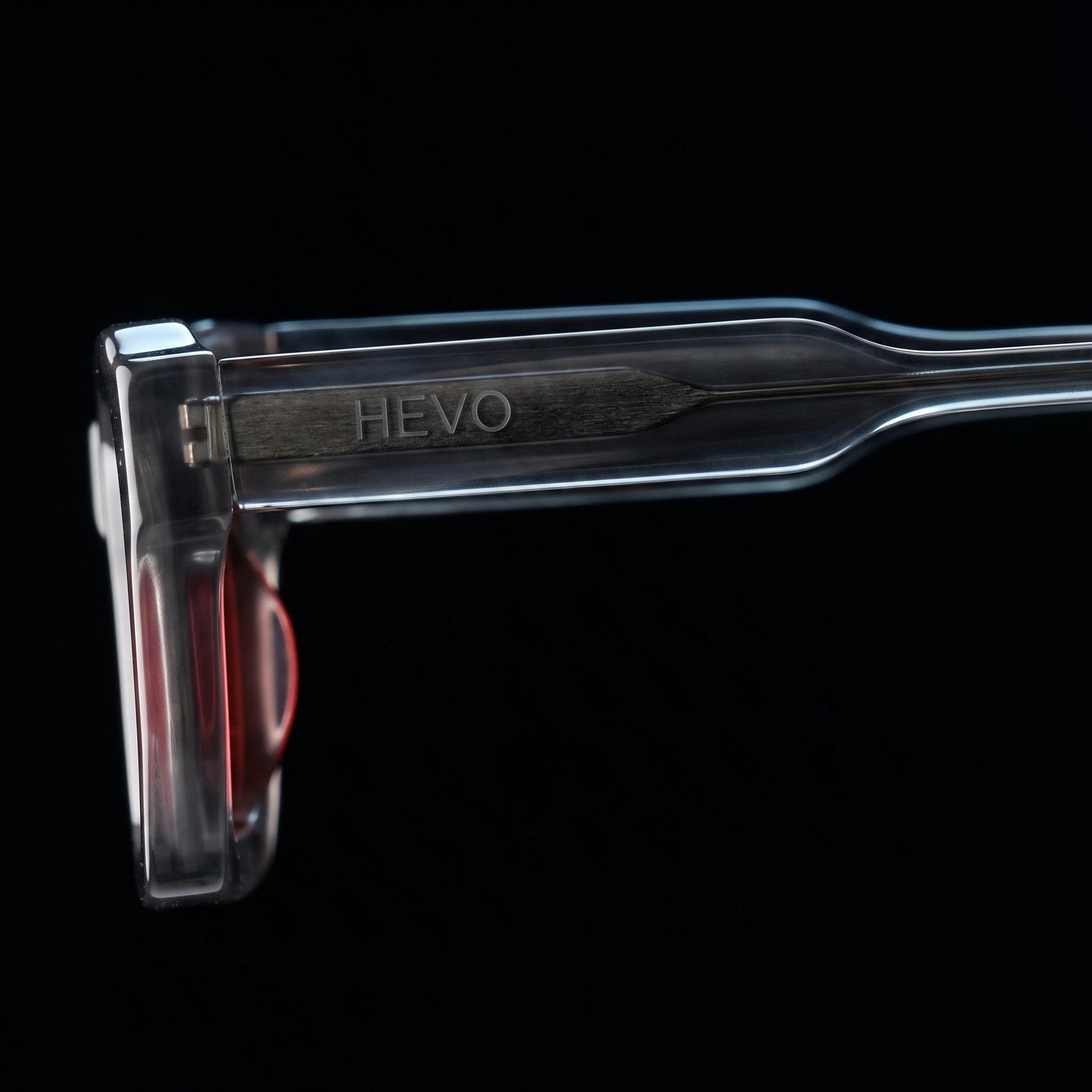 A close-up studio shot of a transparent cosmetic applicator tip with the brand name HEYO embossed vertically on the handle, set against a solid black background.